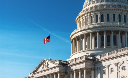 US flag flying at the Capitol building against a blue sky