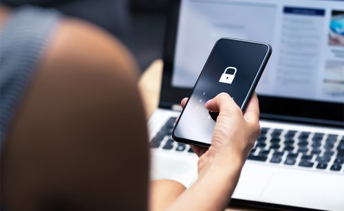 View over a woman's shoulder of her entering a password into a locked smartphone