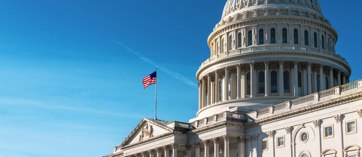 US flag flying at the Capitol building against a blue sky