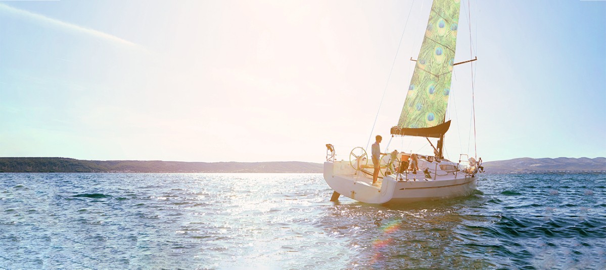 Sailing boat on the ocean with peacock feather patterned sails